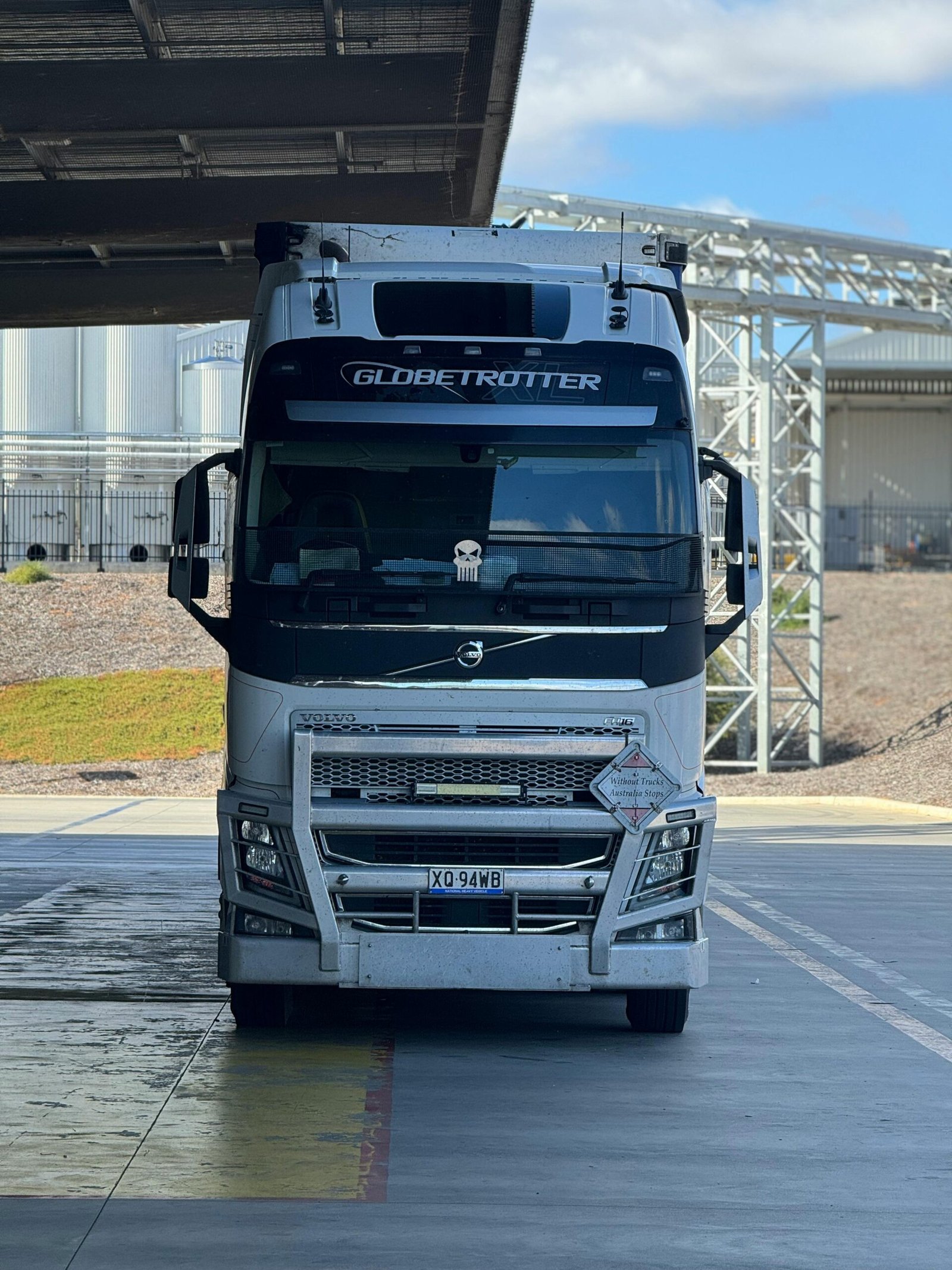 White Globetrotter semi-trailer truck parked outdoors under partial shade.